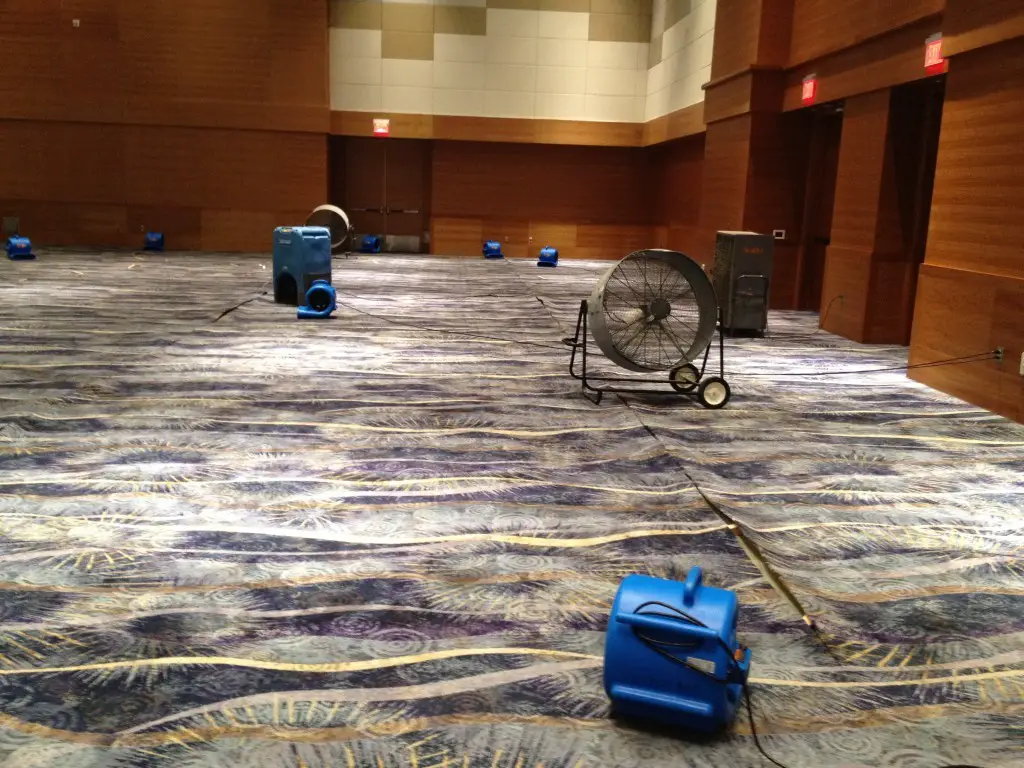Air movers and dehumidifiers drying a large commercial floor after water damage